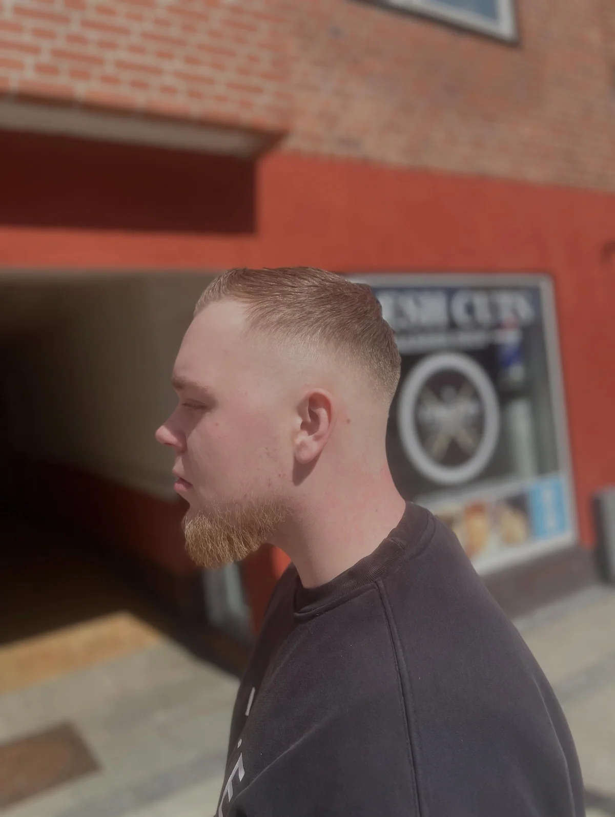 Rødhåret kunde med kort frisure og trimmet skæg foran Freshcuts Barbershop